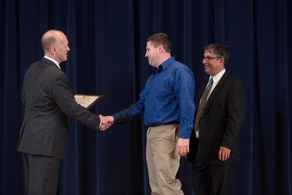 Doctor Potteiger shaking hands with an award recipient in a blue shirt